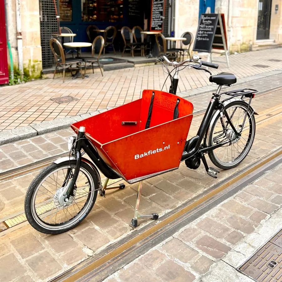 Biporteur Bakfiets.nl à caisse orange électrifié par Mood, garé rue Fondaudège
