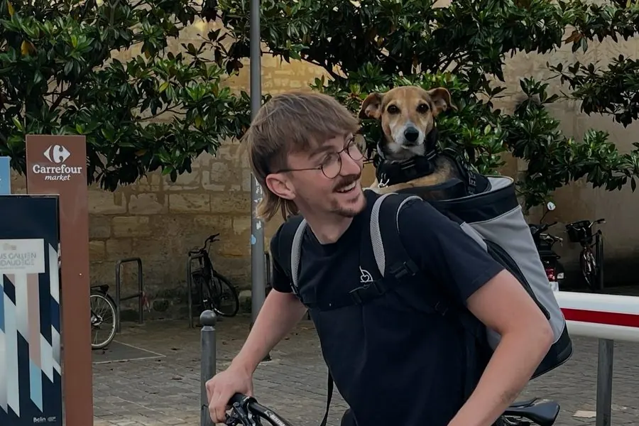 Paul sur un vélo cargo, son chien dans le sac à dos