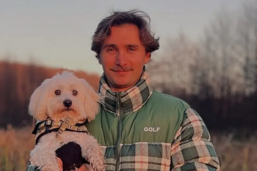 Pierre dans un champ au coucher du soleil, son chien dans les bras