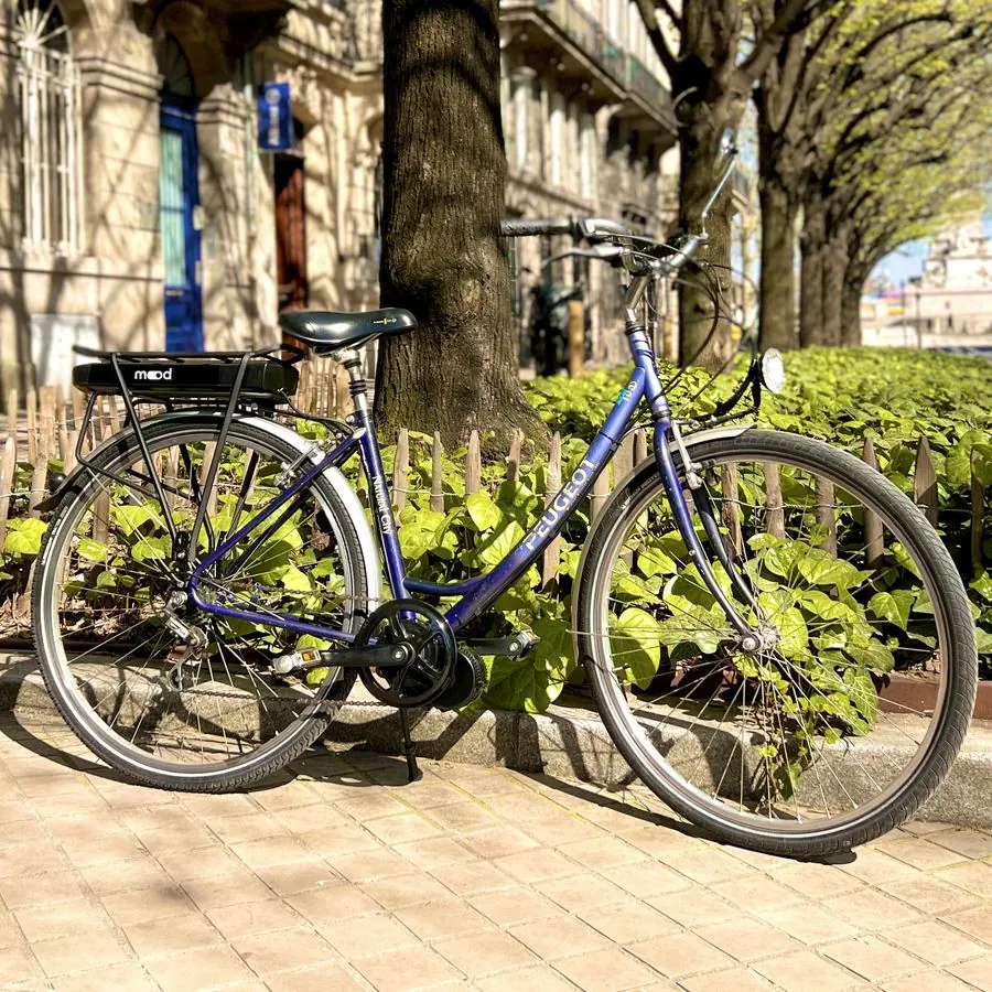 Vélo de ville Peugeot bleu électrifié par Mood, batterie sur le porte-bagage